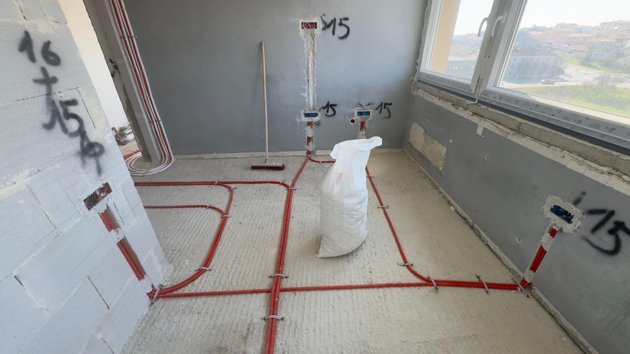 Conduit runs laid across a room floor before the screed is poured.