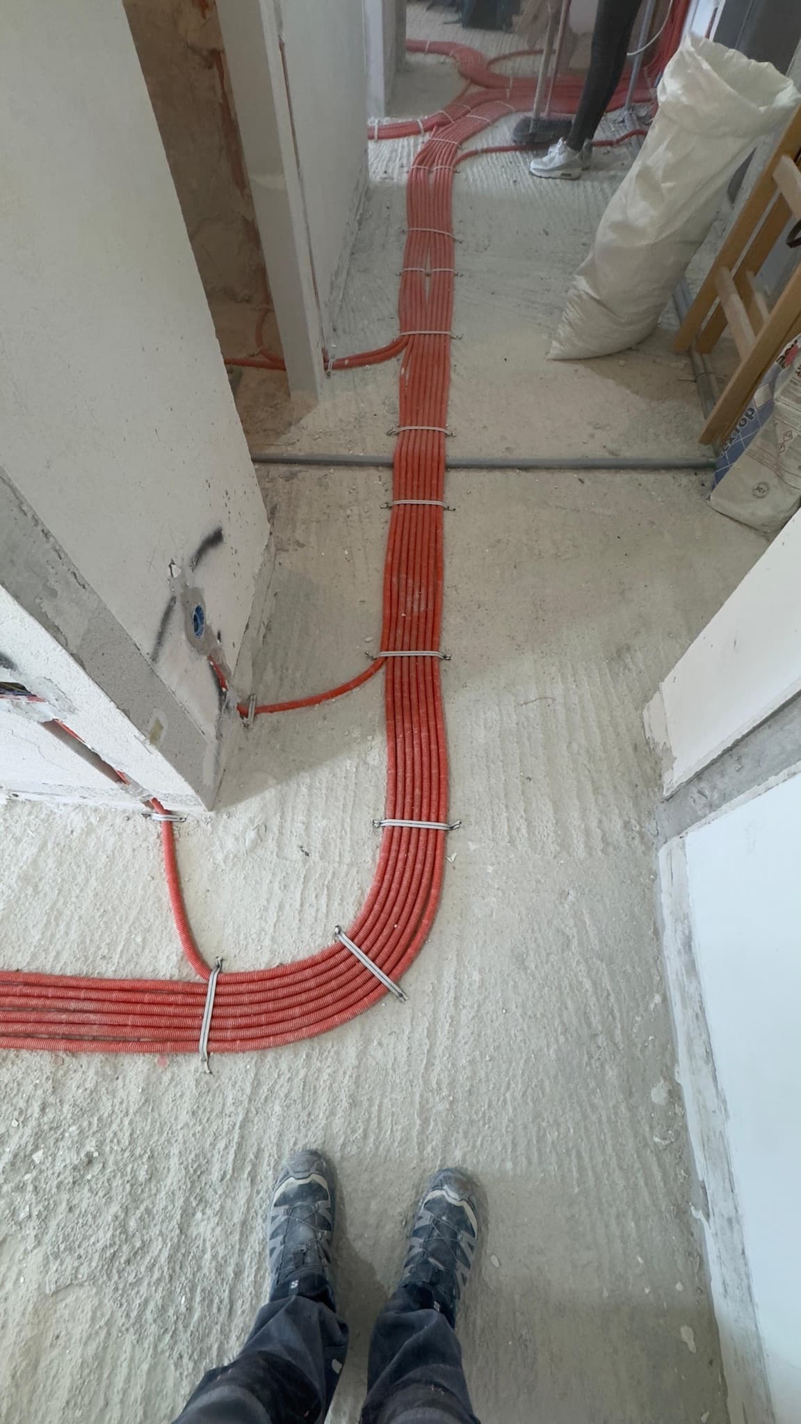 A bundle of conduits clipped down along the route between two rooms.