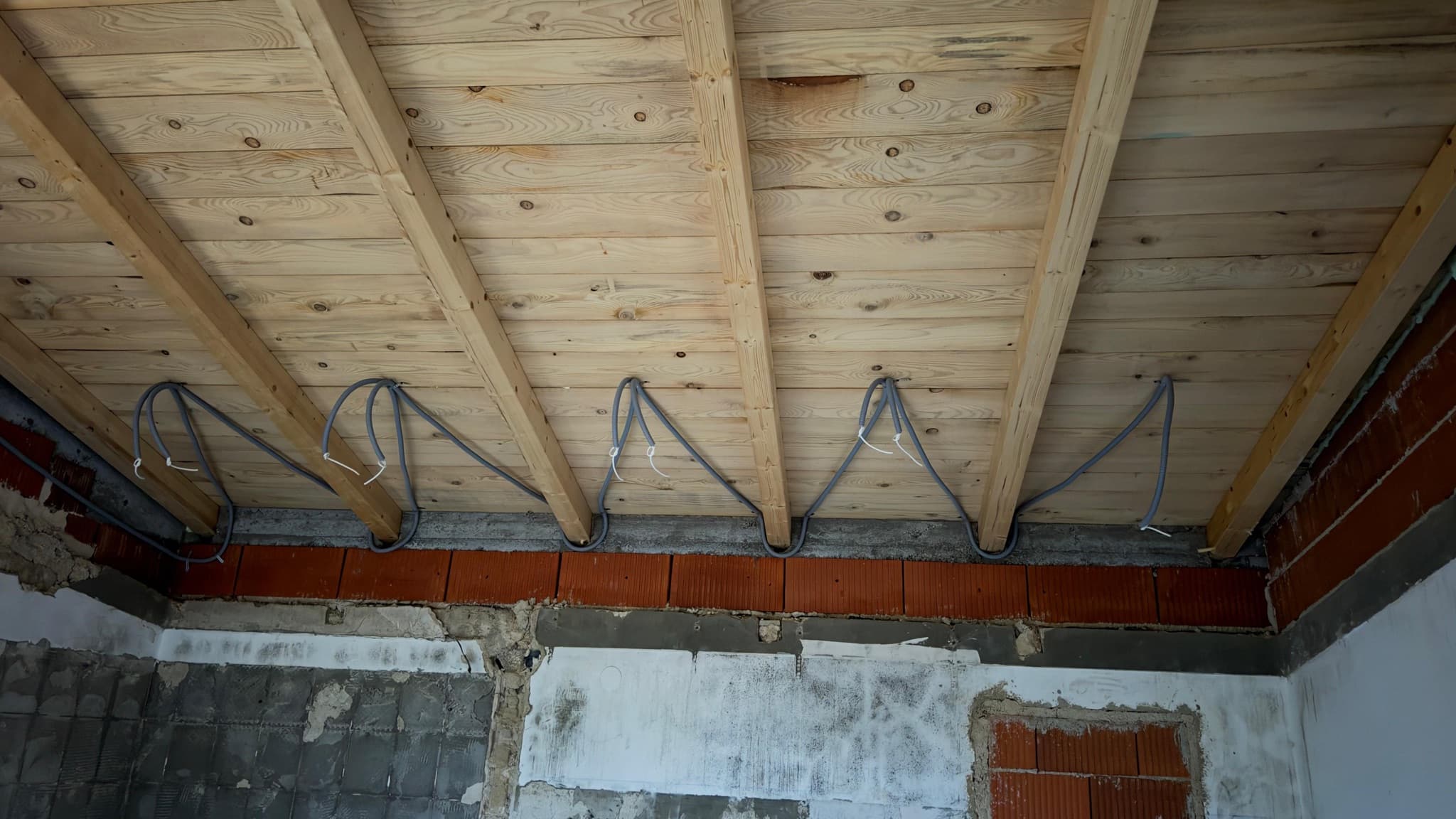 Electrical cabling run along a timber roof structure.