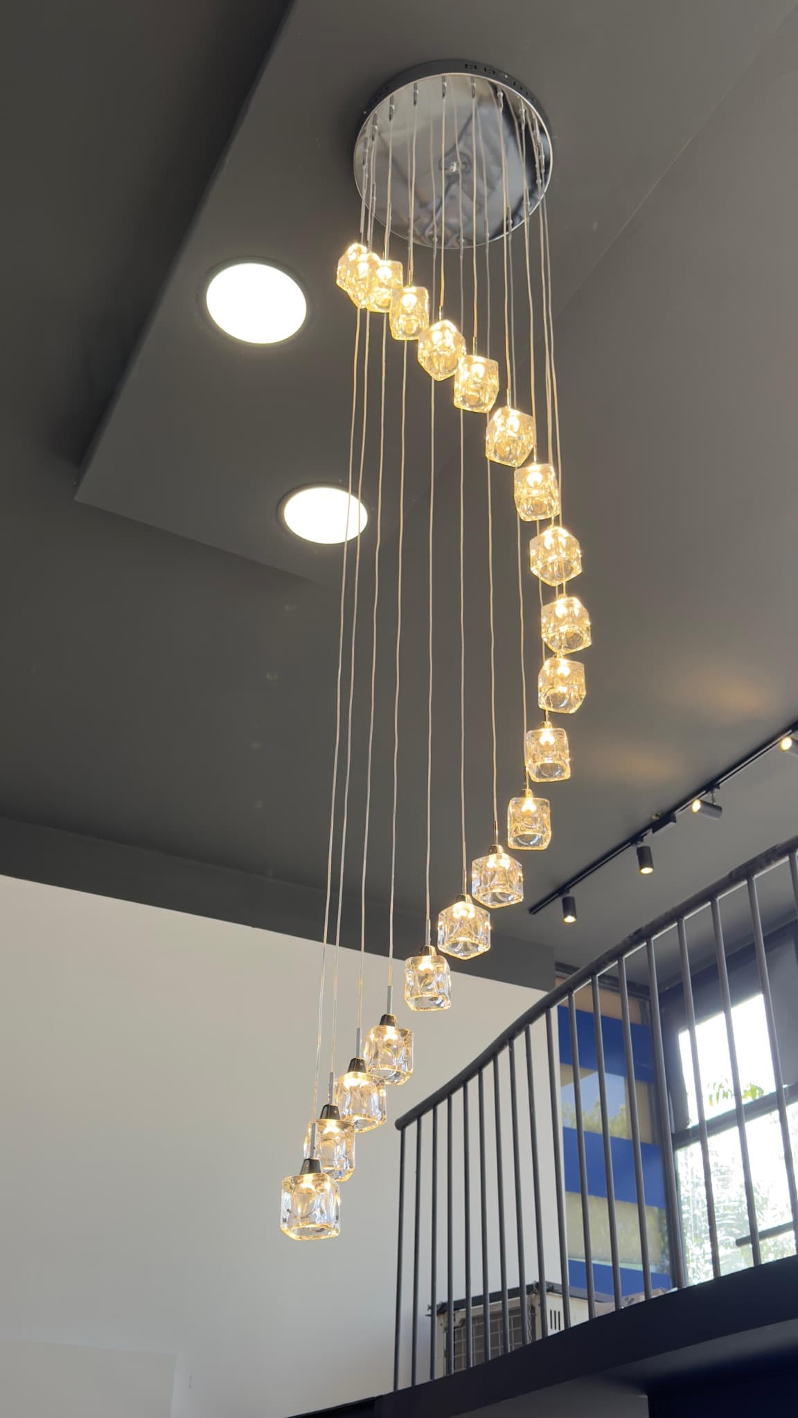 Spiral pendant chandelier in a double-height space beside the stair balustrade.