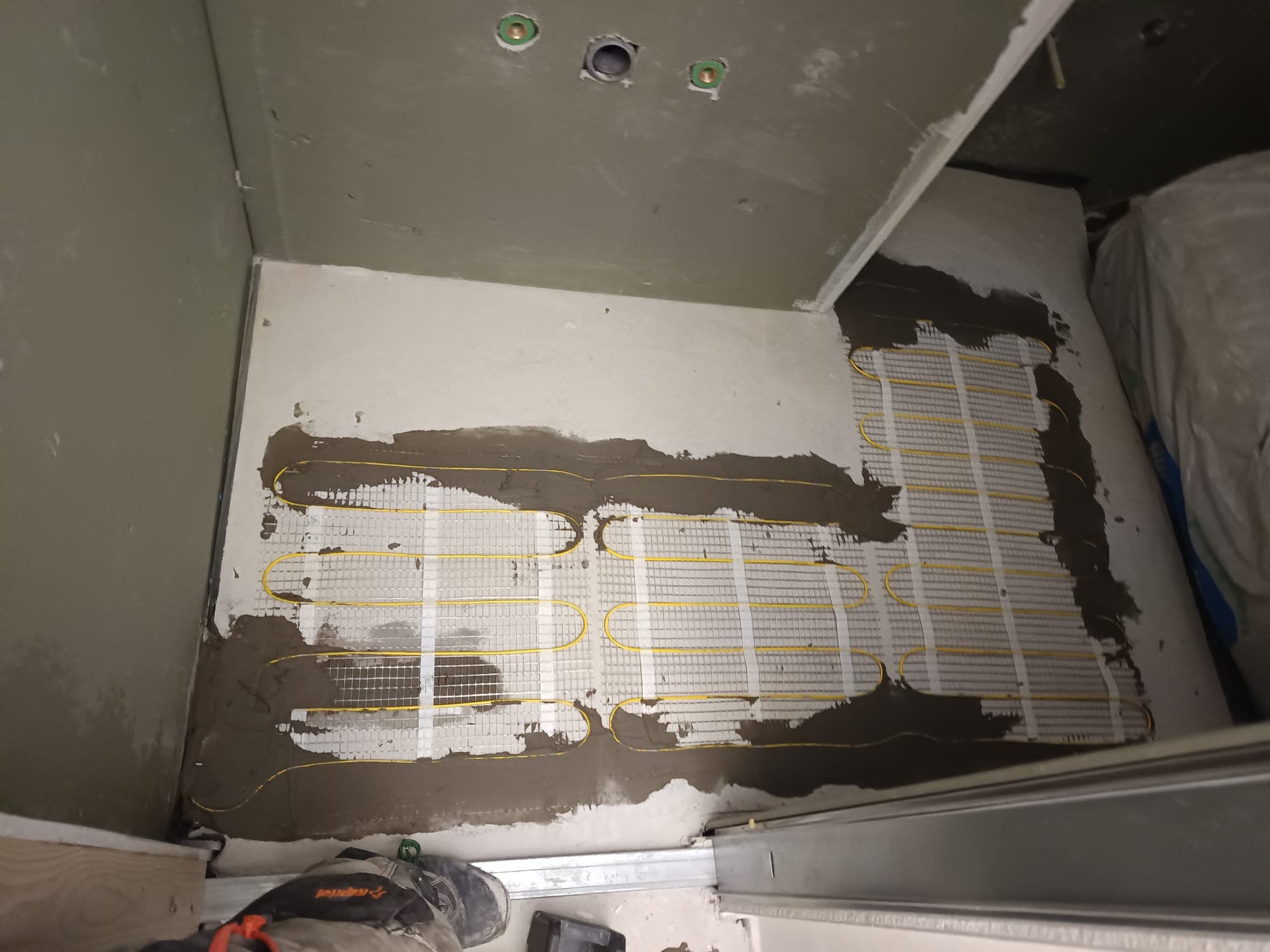 Heating mats cut to the bathroom layout and bonded to the substrate.