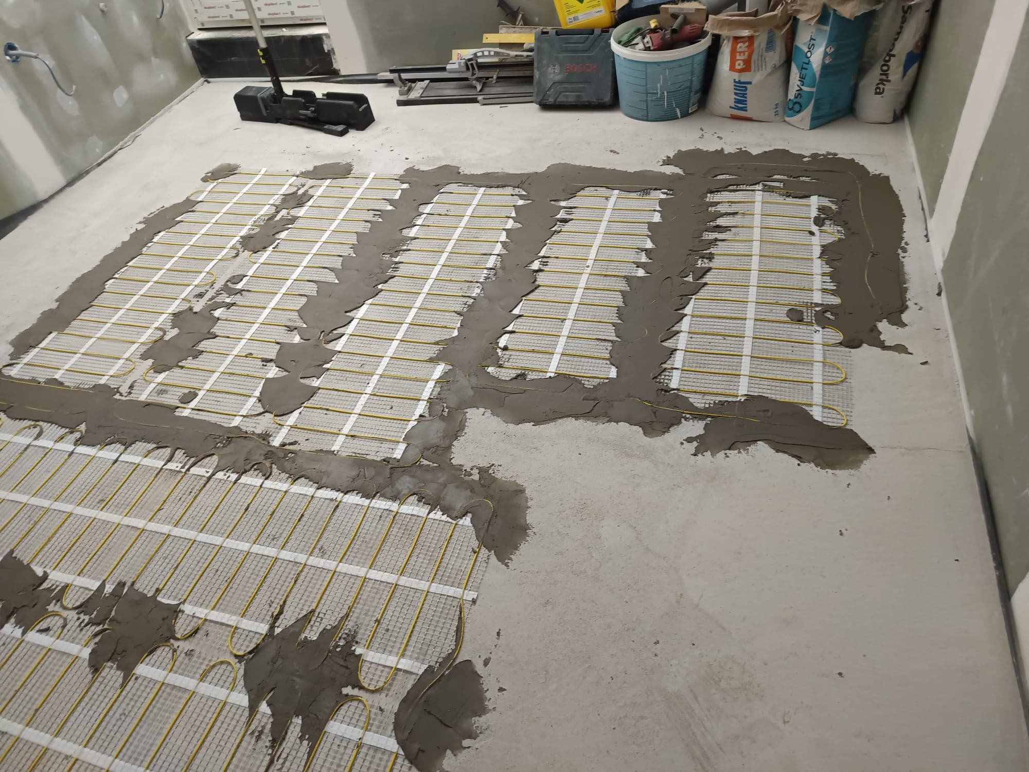Electric underfloor heating mats laid across a room floor before the screed is poured.