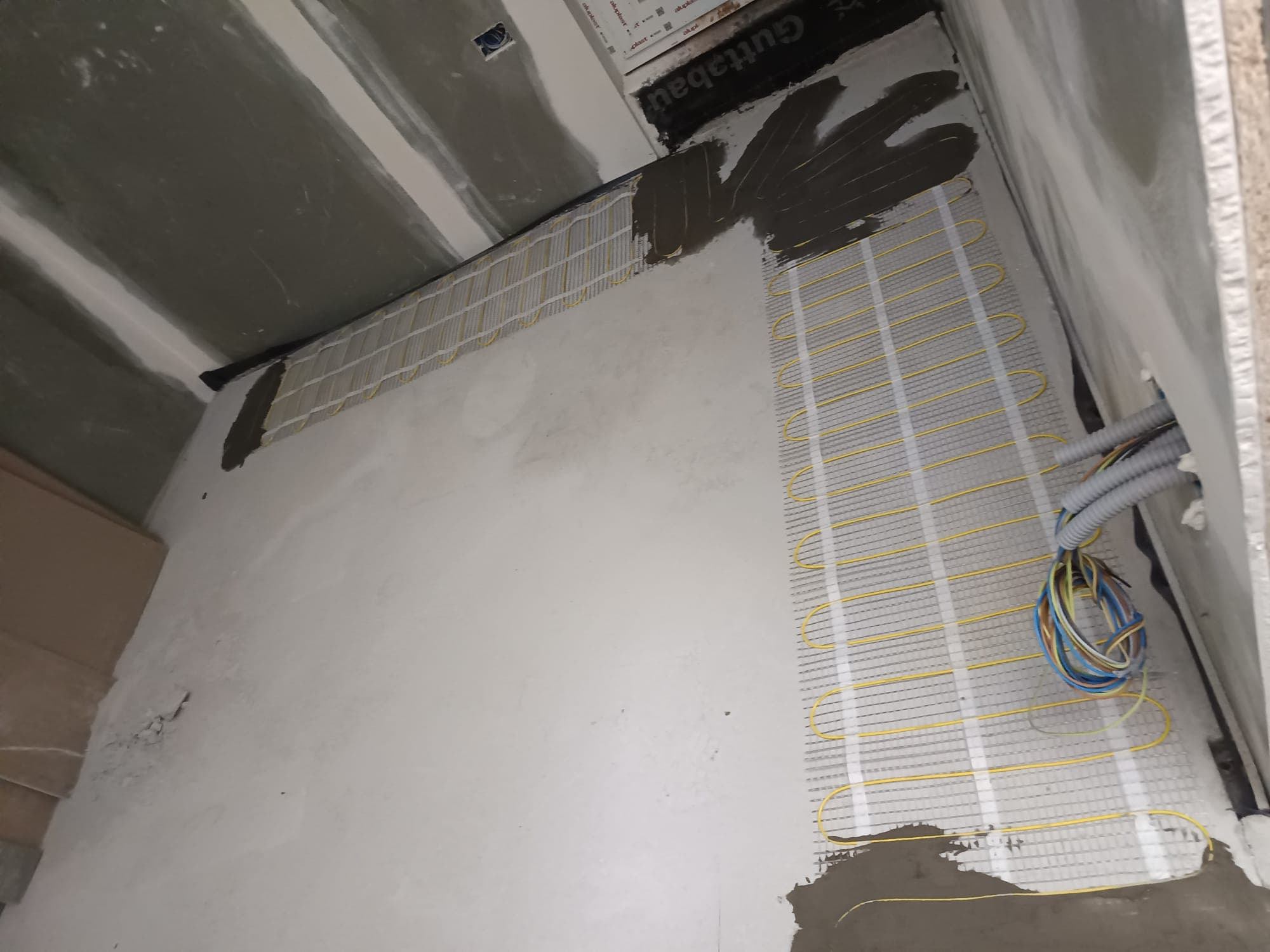 Heating mats in a bedroom with the connecting cable prepared in protective conduit.