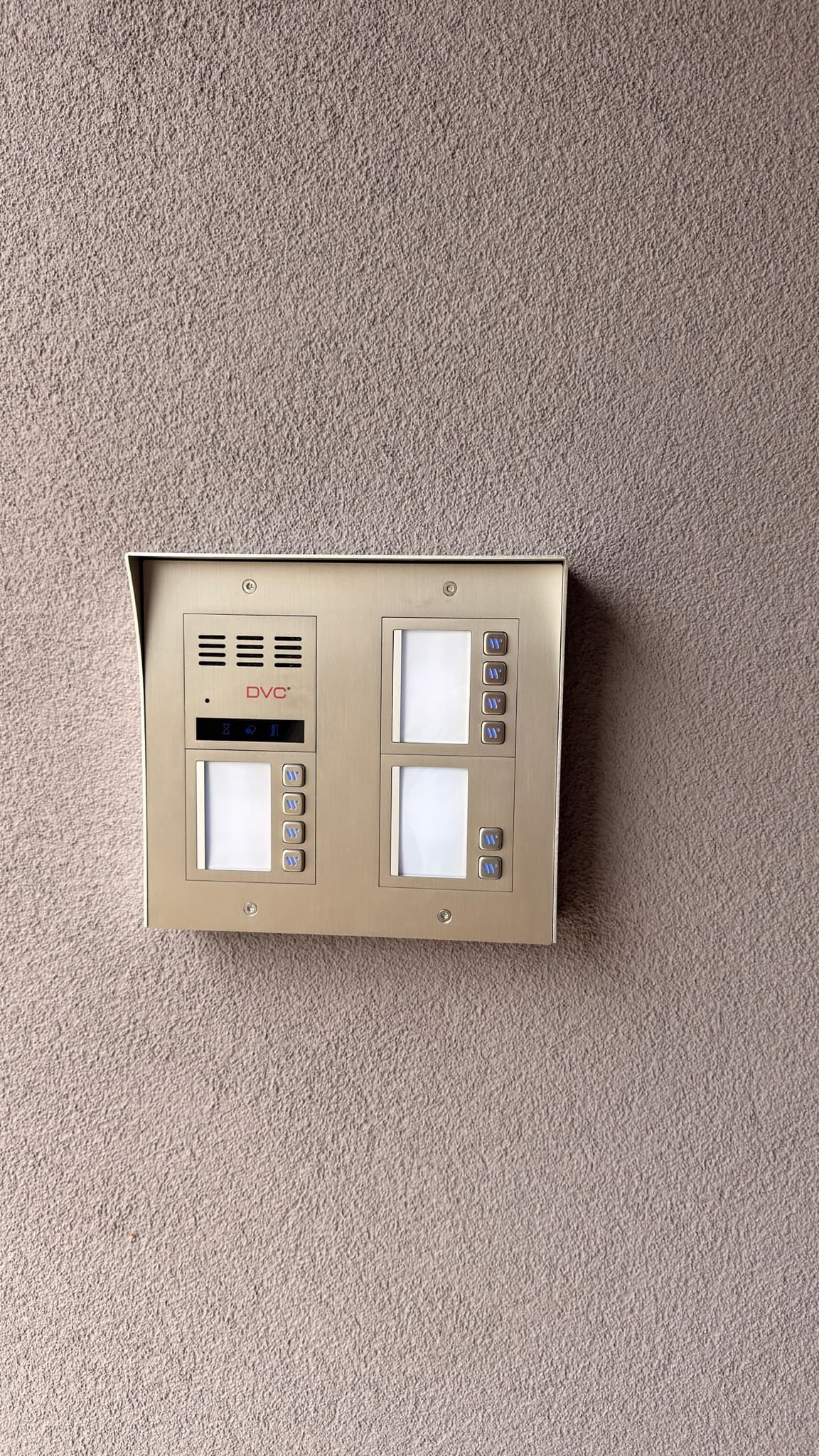 Multi-button intercom panel mounted on the facade of an apartment building.