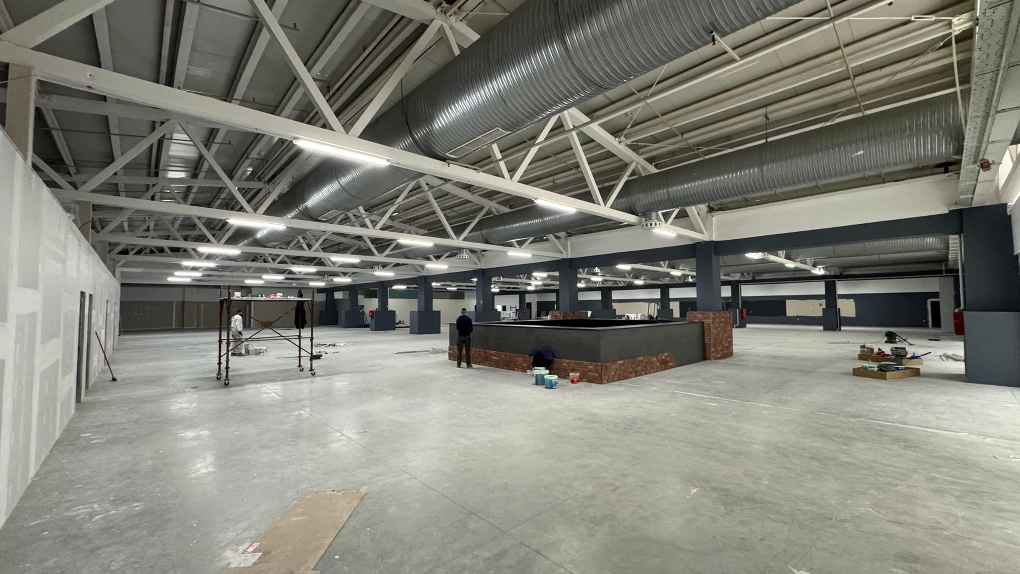 Industrial lighting in a large commercial hall during fit-out.