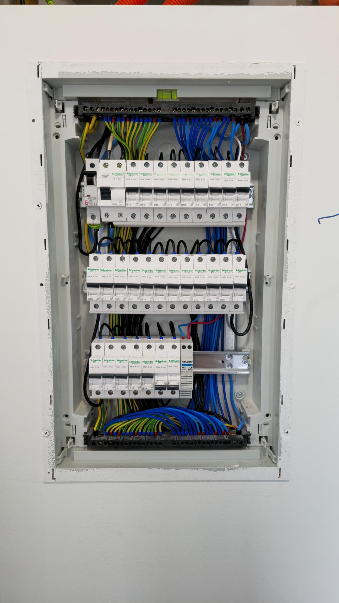 Open switchboard cabinet with three rows of circuit breakers and neatly dressed cabling.
