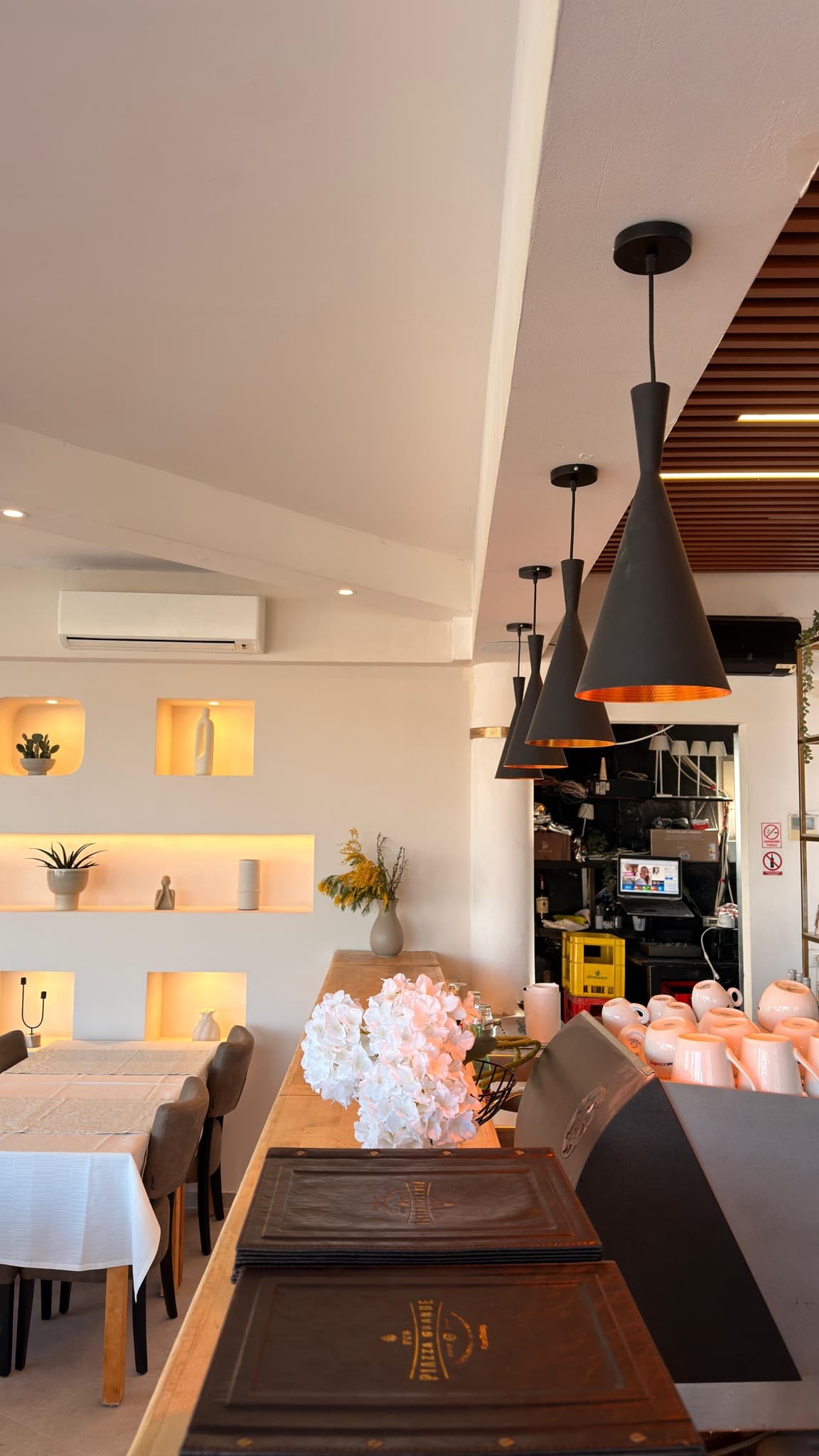 Pendant lights above a table and lit niches in a hospitality venue.
