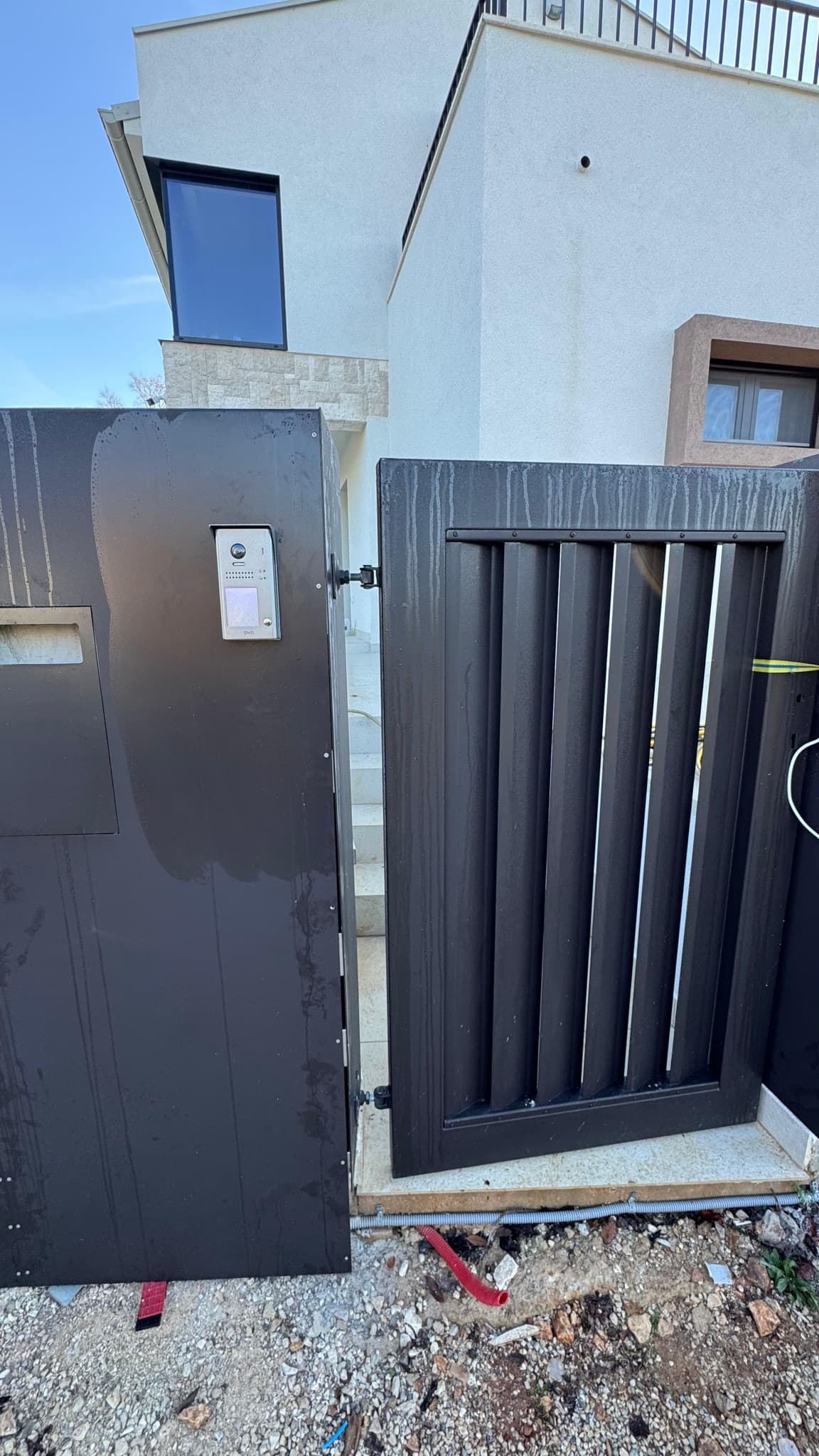 Pedestrian gate with a built-in video intercom in front of a family home.