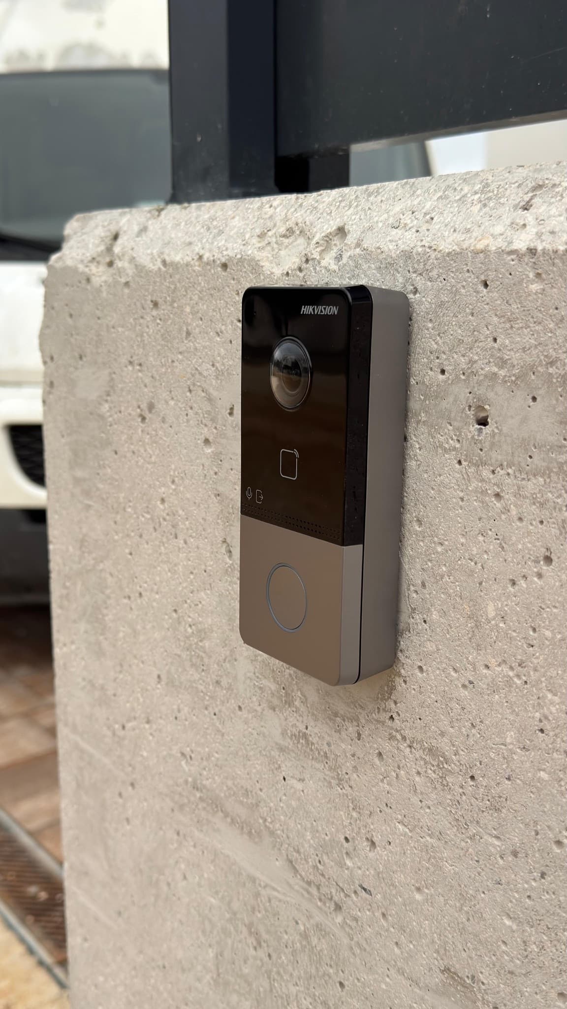 Outdoor video intercom unit with a camera mounted on a concrete gate pillar.